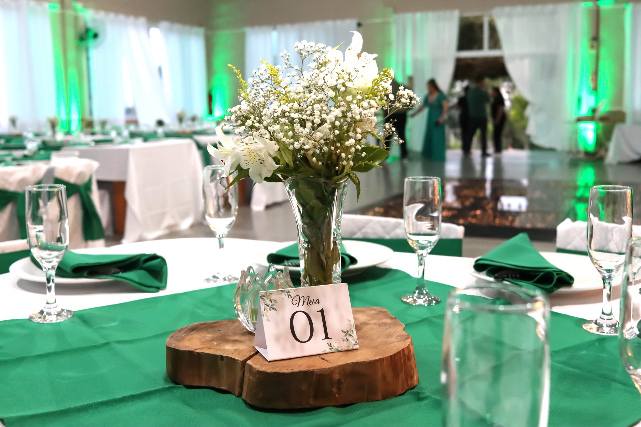 Mesa do bolo decorada com arranjos florais e iluminação aconchegante